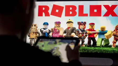 A child poses as he plays a video game on a tablet on the online game platform and game creation system Roblox developed by Roblox Corporation in Terville, northeastern France on March 11, 2026. (Photo by Jean-Christophe VERHAEGEN / AFP)