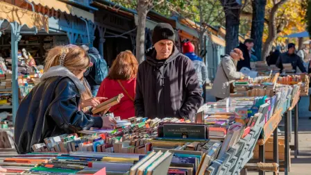 Gente revisando libros en los puestos de segunda mano en la Cuesta de Moyano de Madrid.