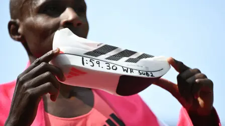 Kenya's Sabastian Sawe poses with his new world record time written on his running shoe at the finish of the 2026 London Marathon in central London on April 26, 2026. Kenya's Sabastian Sawe broke the two-hour mark for the first time in history on Sunday in winning the London Marathon. (Photo by JUSTIN TALLIS / AFP) / Restricted to editorial use - sponsorship of content subject to LMEL agreement.