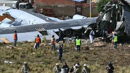 Rescue teams, military personnel, and forensic officers work at the site of the crash of the Bolivian Air Force Lockheed C-130 plane (FAB-81) in El Alto, near La Paz, on February 28, 2026. At least 20 people died on February 27 in a military plane crash in Bolivia that was carrying cash and crashed while landing at El Alto Airport, near La Paz, authorities reported. (Photo by AIZAR RALDES / AFP)