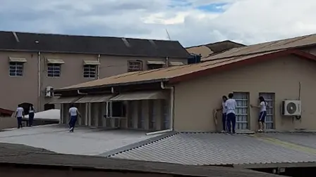 Students of Instituto Sao Jose school take cover on the roof while a teenager invades the school, shooting and killing two staff members and wounding a third staff member and a student, authorities reported, in the city of Rio Branco, Acre state, Brazil, on May 5, 2026. The attack occurred in the afternoon at a school in Rio Branco, the capital of the state of Acre, and a 13-year-old boy was arrested by police, the state government said in a statement. (Photo by AFP)