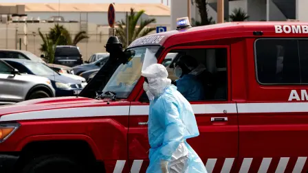 Una persona con ropa protectora camina junto a una ambulancia durante una operación de evacuación de pacientes sospechosos de hantavirus, tras un brote en el crucero MV Hondius, en Praia, Cabo Verde.