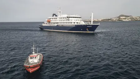 This aerial view shows a boat heading towards the port from the cruise ship MV Hondius, stationary off the port of Praia, the capital of Cape Verde, on May 6, 2026. Evacuations were taking place on May 6, 2026 from a cruise ship stricken with a deadly outbreak of hantavirus, the World Health Organization said, as experts confirmed a rare strain that can be transmitted between humans.Three people, two crew members and one other person, thought to be infected with the virus were being taken off the MV Hondius, anchored off Cape Verde, the WHO said. (Photo by AFP)