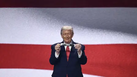 US President Donald Trump shows the card reading USA during the draw for the 2026 FIFA Football World Cup taking place in the US, Canada and Mexico, at the Kennedy Center, in Washington, DC, on December 5, 2025. (Photo by Brendan SMIALOWSKI / AFP)