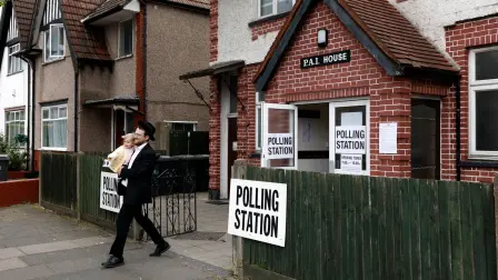 Una persona que lleva a un niño en brazos sale de un colegio electoral habilitado para las elecciones locales en la zona de Golders Green.
