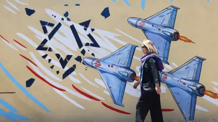 Una mujer iraní pasa junto a un mural antiestadounidense y antiisraelí pintado en una pared de la capital, Teherán.