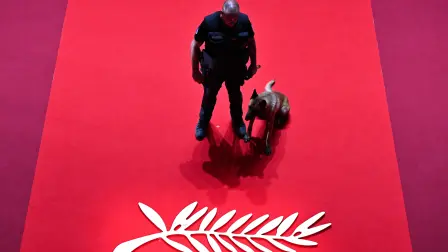 A gendarme of the canine unit patrol and a dog stand next to the logo of the 77th edition of the Cannes Film Festival inside the Grand Auditorium Louis Lumiere, ahead of the Closing Ceremony, in Cannes, southern France, on May 25, 2024. (Photo by Antonin THUILLIER / AFP)
