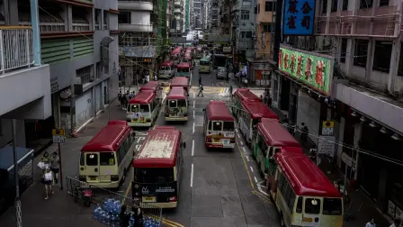 Red mini buses are seen parked on a street in Hong Kong on August 11, 2023. (Photo by ISAAC LAWRENCE / AFP)