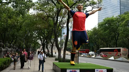 People walk past a giant sculpture depicting a Spain's football player, as part of the urban exhibition "Gigantes del Futbol" (Giants of Soccer) by Mexican artisans from the Zion Art Studio workshop, ahead of the FIFA 2026 World Cup in Mexico City on June 1, 2026. (Photo by Yuri CORTEZ / AFP)