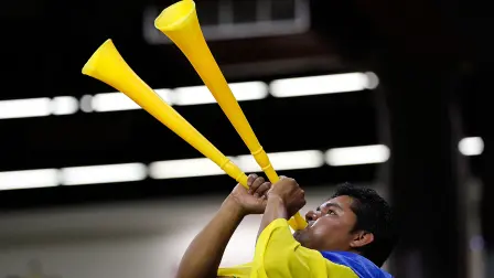 Fanático de futbol tocando una vuvuzela.