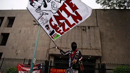 Un manifestante con una bandera del Ejército Zapatista de Liberación Nacional (EZLN) participa en una manifestación organizada por la CNTE antes del inicio de la Copa Mundial de la FIFA 2026, frente al edificio de la Secretaría de Gobernación en la Ciudad de México.