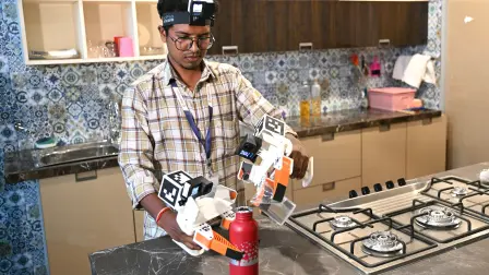This photograph taken on May 13, 2026 shows a worker wearing a GoPro camera on his head recording actions through motion capture while filling water bottles inside a model kitchen at AI data company Objectways' office in Tamil Nadu's Karur district. Developers think feeding first-person footage, called "egocentric data", into specialised AI models will help robots copy humans. The humanoid robot market is booming, with investment bank Morgan Stanley predicting there could be over a billion in use by 2050, mostly for industrial and commercial purposes. In India, the emerging field of spatial AI is providing new employment -- for now. (Photo by R.Satish BABU / AFP)