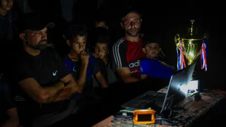 El exfutbolista palestino Fadi Al-Arawi mira un partido del Mundial 2026 en una computadora junto a otras personas en Khan Younis, en la Franja de Gaza.