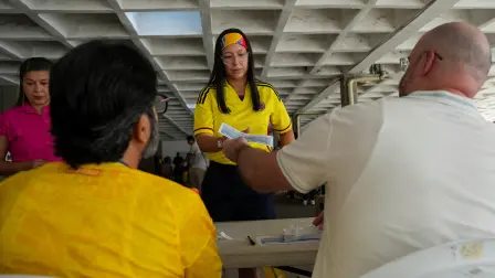 A poll worker hands out a ballot as people vote in a runoff between right-wing presidential candidate Abelardo De La Espriella and leftist candidate Ivan Cepeda, in Barranquilla, Colombia, June 21, 2026. REUTERS/Jair Coll