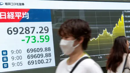 Pedestrians walk past an electronic quotation board displaying the Nikkei Stock Average on the Tokyo Stock Exchange along a street in Tokyo on June 29, 2026. (Photo by Kazuhiro NOGI / AFP)