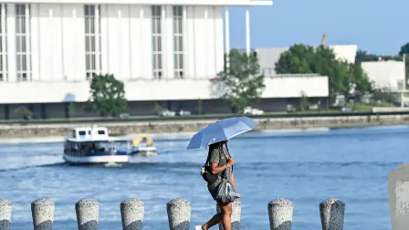 A person uses an umbrella to stay cool while walking along the Potomac River during a heatwave in Washington, DC, on July 1, 2026. Tens of millions of Americans sweltered under furnace-like temperatures this week as central and eastern cities hunkered down for a heat wave set to last through the July 4 holiday weekend. Dozens of local temperature records could be broken, the National Weather Service (NWS) warned, with temperatures in many places to surpass 100 degrees Fahrenheit (38 degrees Celsius) and high humidity pushing the heat index as high as 115 degrees. (Photo by Alex WROBLEWSKI / AFP)