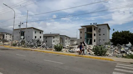 People walk on a street by piles of debris in the aftermath of the June 24 earthquakes, in La Guaira, Venezuela, July 6, 2026. REUTERS/Ricardo Arduengo