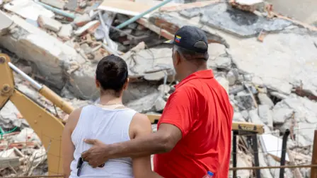 María Alejandra Sanz , de 17 años, abraza a su padre, Alejandro Sanz , con los restos de su edificio de apartamentos al fondo en La Guaira, Venezuela.