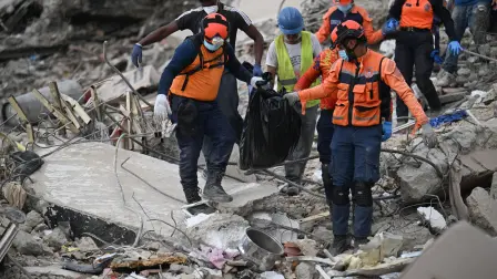 Rescue workers carry a body on the debris of a collapsed building in Caraballeda, La Guaira state, Venezuela, on July 15, 2026, following the June 24 twin earthquakes. The death toll from the earthquakes that struck Venezuela almost three weeks ago has surpassed 4,700, while almost 17,000 people have been injured, an official report released on July 14, 2026 stated. (Photo by Juan BARRETO / AFP)