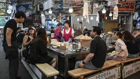 People dine at a food stall at Gwangjang Market in Seoul on July 15, 2026. (Photo by JADE GAO / AFP)