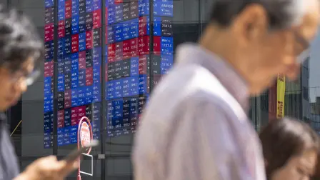 Pedestrians walk past as an electronic quotation board displays the Nikkei 225 stock prices on the Tokyo Stock Exchange in Tokyo on June 16, 2026. (Photo by Kazuhiro NOGI / AFP)