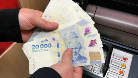 This photo illustration shows a woman holding Argentine Pesos banknotes after withdrawing money from an ATM in Buenos Aires, on May 15, 2026. (Photo by JUAN MABROMATA / AFP)