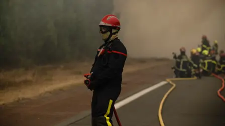 Bomberos rocían agua a lo largo del linde de un bosque durante un incendio forestal cerca de la localidad de Lège-Cap-Ferret, en el suroeste de Francia.