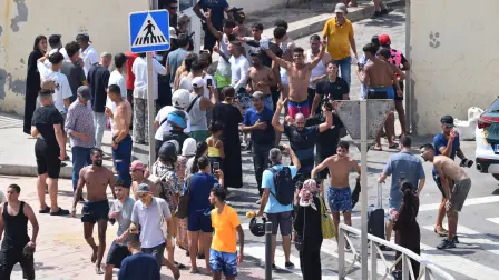 Varios migrantes celebran haber cruzado la frontera, a 30 de julio de 2026, en Ceuta (España). Centenares de personas de origen magrebí han cruzado a lo largo de la mañana de hoy a Ceuta desde Marruecos, a nado y por el espigón, y una multitud está esperando al otro lado de la frontera para poder entrar en la ciudad autónoma de la misma manera. En la última semana lo han hecho ya más de 2.000 migrantes.