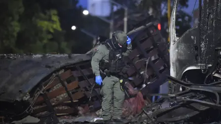 Policías inspeccionan un camión destruido tras la explosión de un coche bomba cerca de una estación de policía en Cúcuta, Colombia; el atentado dejó al menos 11 personas heridas.