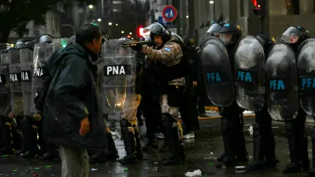 Un policía antidisturbios apunta con una escopeta durante una protesta frente al Congreso Nacional en Buenos Aires.