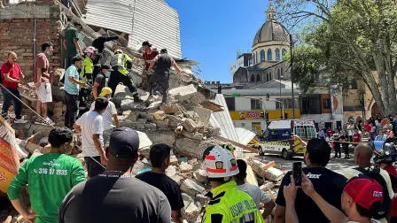 Residentes y personal de emergencia excavan entre los escombros de un edificio parcialmente derrumbado tras un terremoto en Pereira, Colombia.