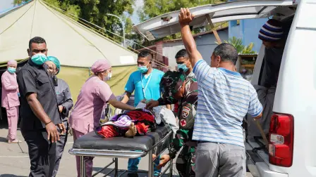 Personal sanitario y de emergencia traslada a un paciente en camilla desde una ambulancia en un hospital regional tras un terremoto que se sintió en Ruteng.