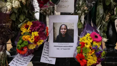 Una foto (C) del difunto profesor de Cambridge, Jason Arday, aparece junto a ofrendas florales colocadas en la valla por sus seguidores alrededor del Senate House de la Universidad de Cambridge.