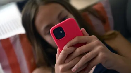 A teenager looks at her smartphone in Brussels on July 7, 2026. The European Commission estimated, on July 6, 2026, that the French bill banning social media access for children under 15 was not fully compatible with European Union law, while reaffirming its support for the initiative. Like France, Spain and Denmark are also working on the introduction of a digital age of majority to follow Australia's example, who became in December 2025 the first country to implement such a law. (Photo by Nicolas TUCAT / AFP)
