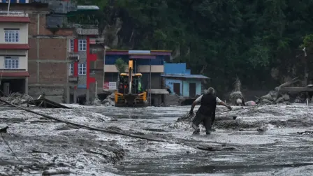 A resident walks along a street covered in mud following flash floods and a landslide disaster in Devighat, in Nepal's Nuwakot district on August 26, 2026. A massive flood and landslide disaster on the Nepal-Tibet border killed at least 103 people on August 26, 2026 and left several hundred missing, many of them foreign tourists. Aid workers said entire settlements had been "wiped out". Some 403 tourists -- 341 of them foreigners -- were unaccounted for several hours after the disaster struck, according to the tourism ministry. (Photo by PRAKASH MATHEMA / AFP)