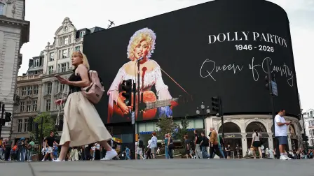 Unas personas pasan junto a un homenaje a la cantante estadounidense de música country Dolly Parton en Piccadilly Circus, un día después del anuncio de su fallecimiento a los 80 años, en Londres.