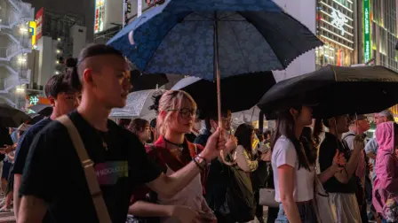 Pedestrians use umbrellas to shelter from the rain while walking on a street in Shinjuku district in Tokyo on August 11, 2026. (Photo by Philip FONG / AFP)