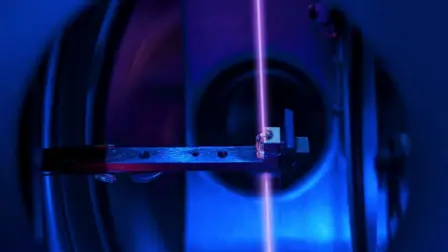 En la imagen se observa un cristal de fluoruro de calcio —alojado en su soporte e integrado con una gran cantidad de núcleos de torio— dentro del sistema de vacío de un reloj nuclear, mientras un haz láser sondea dichos núcleos en un laboratorio de la TU Wien en Viena, Austria. Foto: Reuters