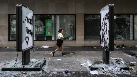Un peatón pasa frente a un comercio saqueado en Lyon, Francia, tras las protestas contra el alto costo de vida que dejaron 1,200 detenidos y 150 policías heridos. Foto: AFP.