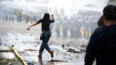Un manifestante corre mientras se utiliza un cañón de agua contra los manifestantes durante una protesta que exige agua potable limpia.