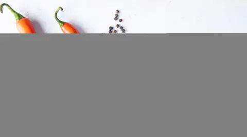 close-up view of peppers and pepper spice on left side and white background with copy space