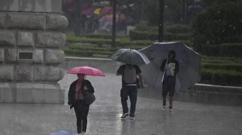 Personas se refugian bajo paraguas de la lluvia en la Ciudad de México.