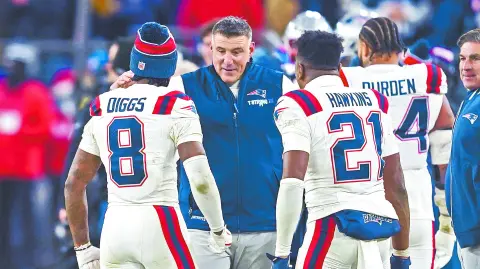 Mike Vrabel habla con Stefon Diggs (8) y Jaylinn Hawkins (21) durante el encuentro con los Ravens.