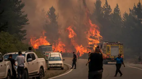Bomberos combaten las llamas para extinguir un incendio forestal en el Monte Pirque, en El Hoyo, en la región patagónica de la provincia de Chubut, Argentina.