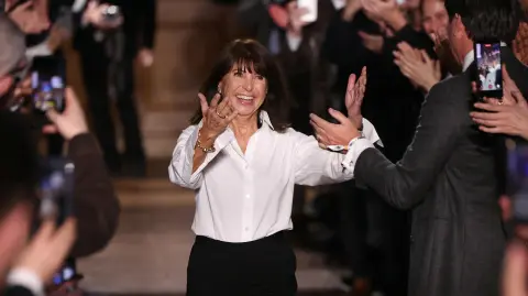 La diseñadora de moda francesa Véronique Nichanian hace un gesto al público al final de su último desfile de la colección prêt-à-porter masculina otoño-invierno 2026/2027 de Hermès.