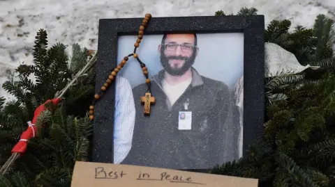 Una foto de Alex Pretti se encuentra en un monumento improvisado en la zona donde fue asesinado a tiros.