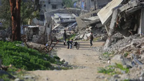 Niños palestinos juegan con una silla de ruedas entre edificios destruidos en Khan Yunis, en el sur de la Franja de Gaza.