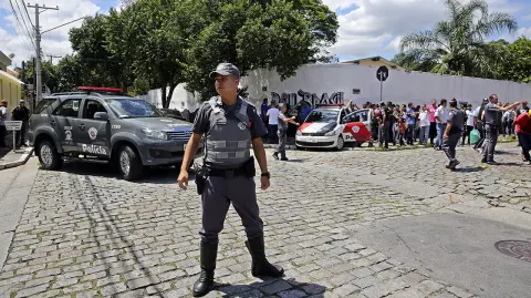 Police officers stand guard outside the Raul Brasil State School in Suzano, the greater Sao Paulo area, Brazil, Wednesday, March 13, 2019. The state government of Sao Paulo said two teenagers, armed with guns and wearing hoods, entered the school and began shooting at students. They then killed themselves, according to the statement. (AP Photo/Andre Penner)