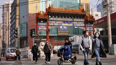 FILE PHOTO: People wearing face masks cross a street in Beijing, following outbreaks of the coronavirus disease (COVID-19) in China