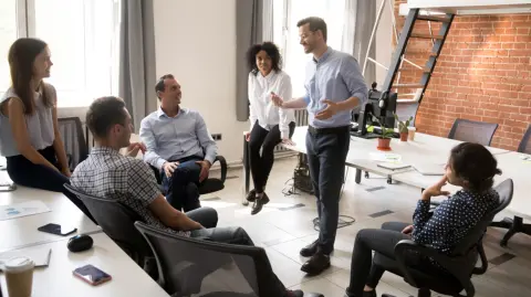 Confident,Male,Leader,,Coach,Talking,With,Multiracial,Group,Of,Office